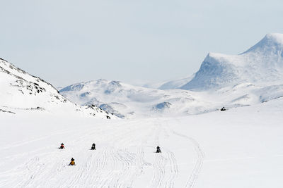 People on snowmobiles in mountains