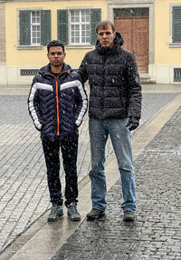 Portrait of friends standing on street in rain