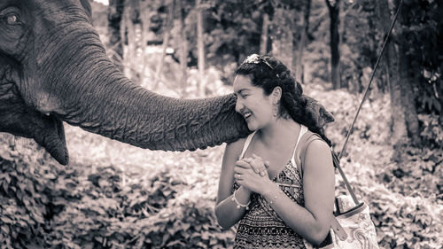 Young woman playing elephant at forest