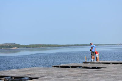 Father and son standing on pier over lake