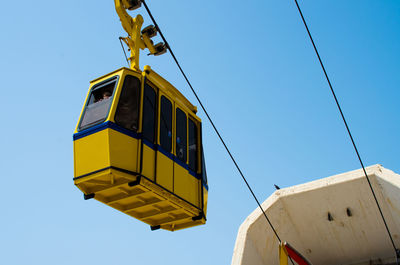 Low angle view of yellow flags against clear blue sky