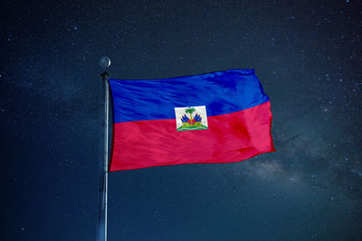 Low angle view of haiti flag against star field sky