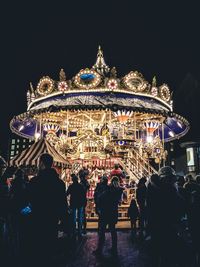 People in amusement park against sky at night