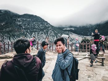 Rear view of people walking on mountain against sky