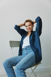 Young woman sitting on chair against clear sky