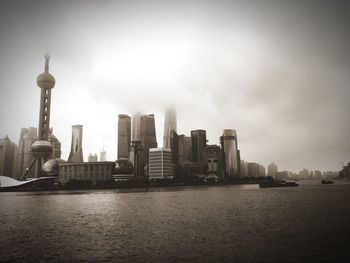 Oriental pearl tower by lake against sky in city