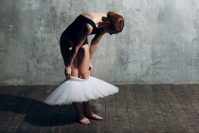 Full length of ballet dancer wearing tutu against gray wall