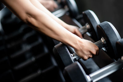 Cropped hands of woman holding dumbbells