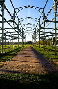 Empty footpath in field against clear sky