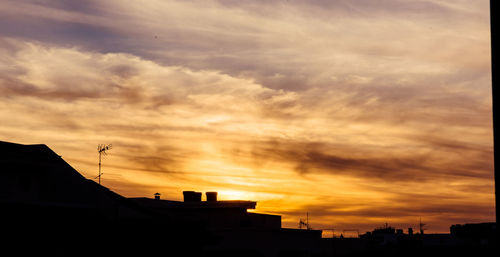 Low angle view of silhouette buildings against dramatic sky