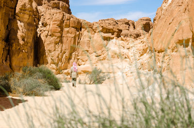 Rear view of woman on rock formation against sky