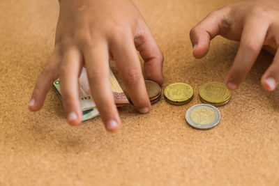 Close-up of hands counting coins and paper currency on table