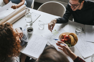 High angle view of business people planning strategy at desk with fruits at office