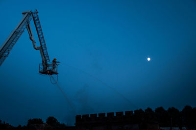 Low angle view of firefighter spraying water on building at dusk