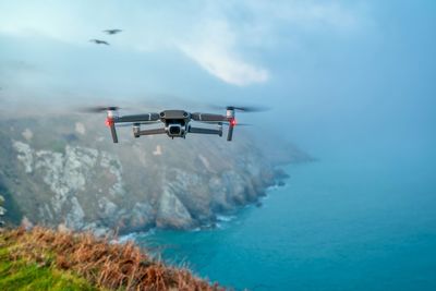 Drone flying over sea against blue sky