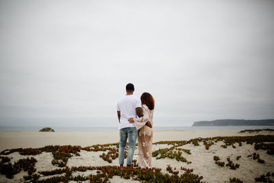 Rear view of couple standing on land against sky