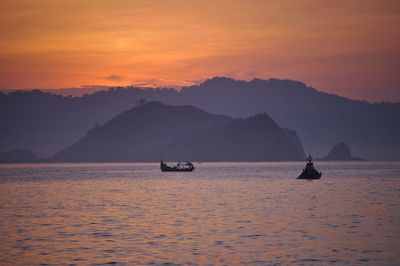 Boats on sea against orange sky