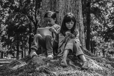 Friends sitting on tree trunk against plants