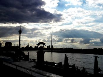 Silhouette of city against cloudy sky