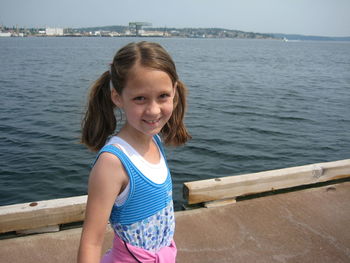 Portrait of smiling girl standing by sea on pier