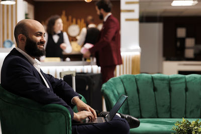 Side view of man using mobile phone while sitting in cafe