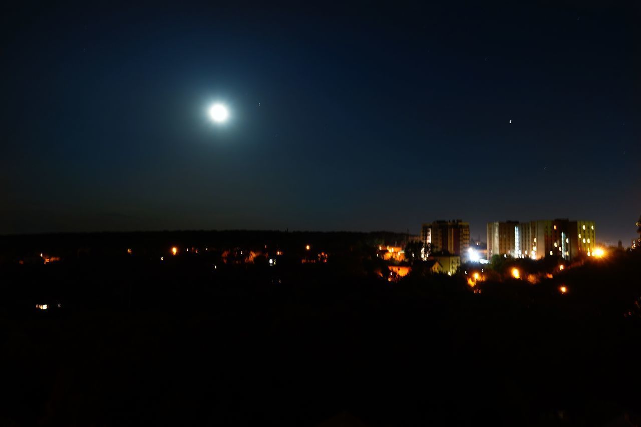 ILLUMINATED BUILDINGS IN CITY AGAINST SKY AT NIGHT