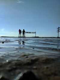 Men standing on beach against sky