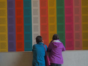 Rear view of couple standing against multi colored wall