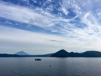 Boats in sea with mountain range in background