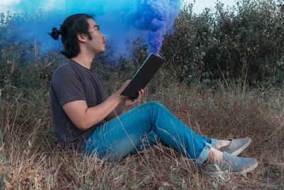 Side view of young man using mobile phone outdoors