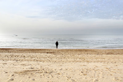 Woman walking at beach against sky