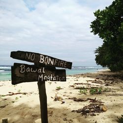 Information sign on beach against sky