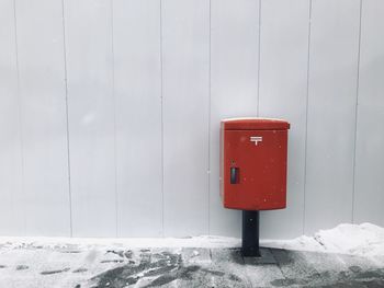 Red mailbox on snow covered wall