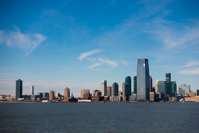 Sea by modern buildings against sky in city