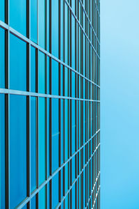 Low angle view of glass building against clear blue sky