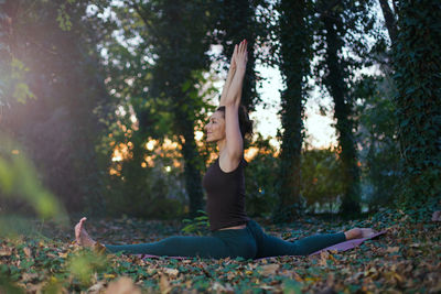 Woman exercising while lying down by tree at park