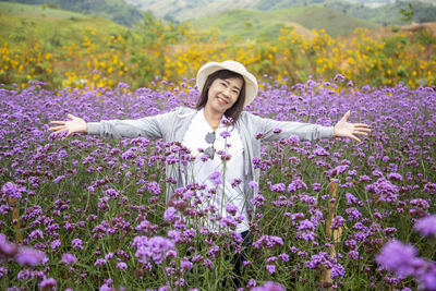 Woman standing by purple flowers on field