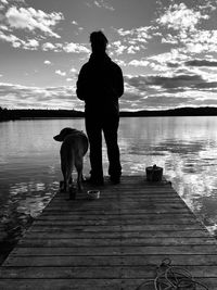 Rear view of man with dog standing on pier