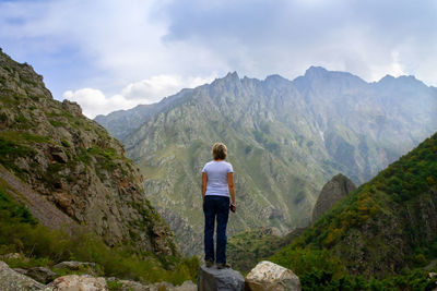 Rear view of woman looking at mountains against sky