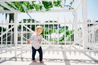 Full length portrait of boy standing on railing