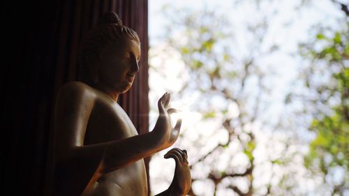 Low angle view of statue against window at home