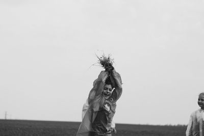 Young woman standing on field against clear sky