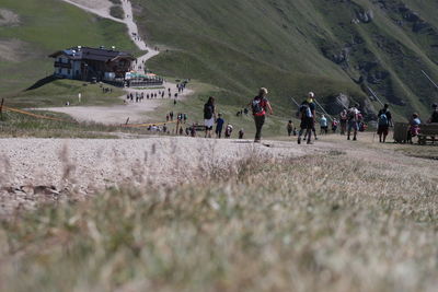 Surface level hikers walking on field against mountain