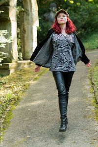 Full length portrait of young woman walking in park
