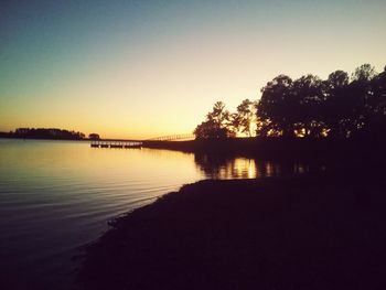 Scenic view of lake against clear sky during sunset