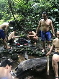 People on rock against trees in forest