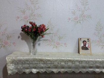 Flower vase on table against wall at home