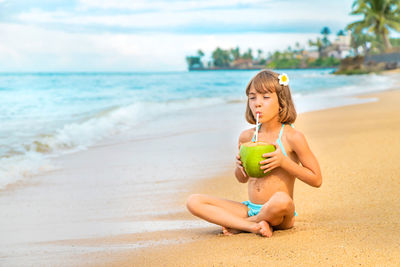 Girl drinking coconut water at beach