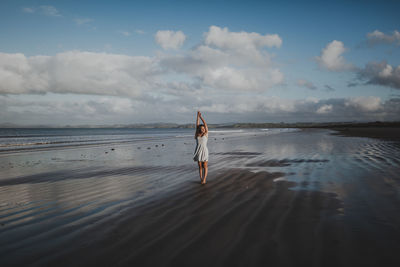 Rear view of man standing on beach against sky