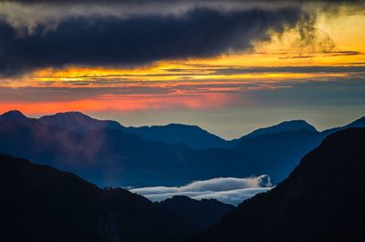 Scenic view of mountains against dramatic sky during sunset